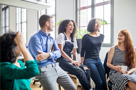 Group of employees sitting in office laughing